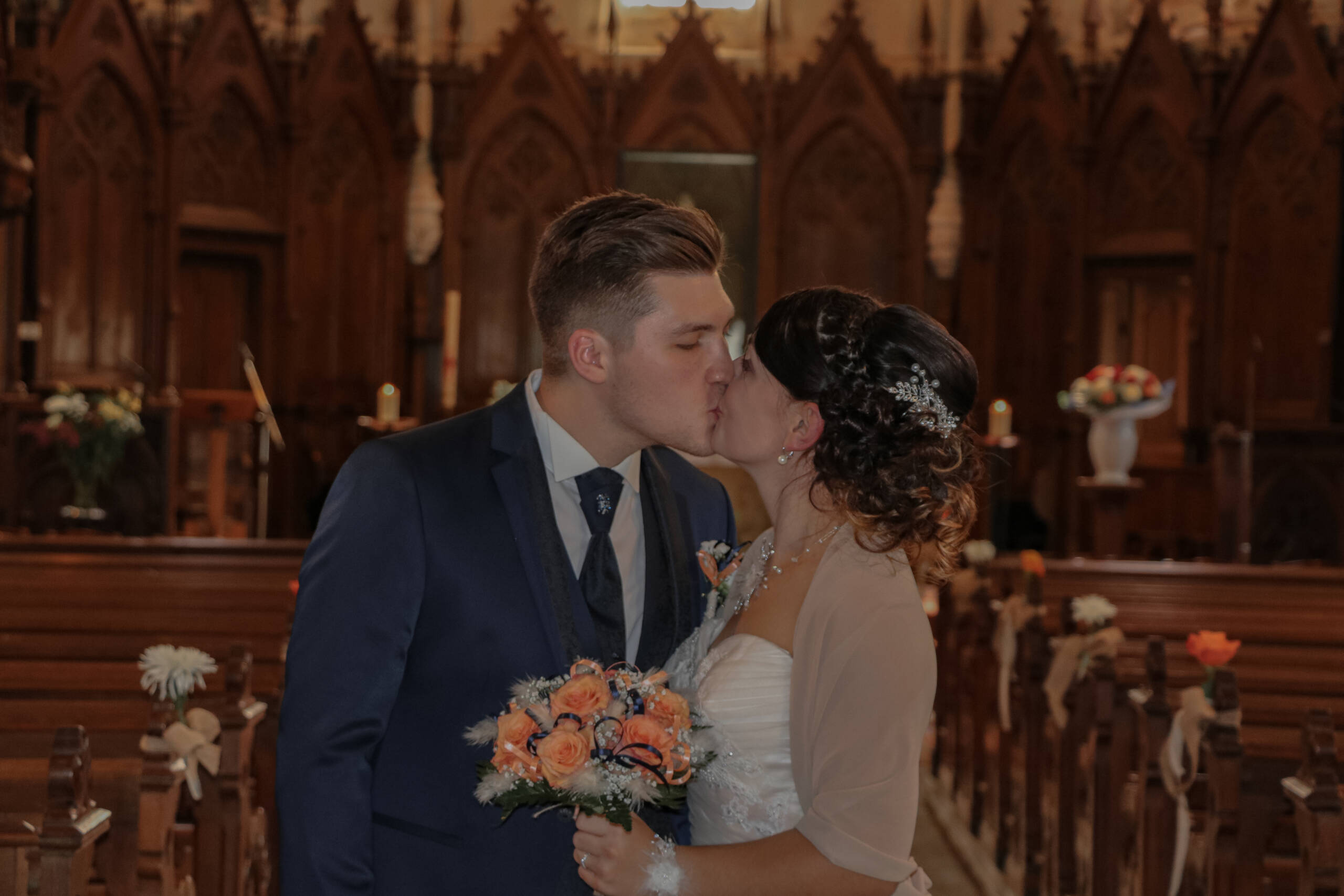 Mariés s'embrassant en sortant de l’église après leur cérémonie religieuse pendant leur mariage, réalisée par Solène photographe.