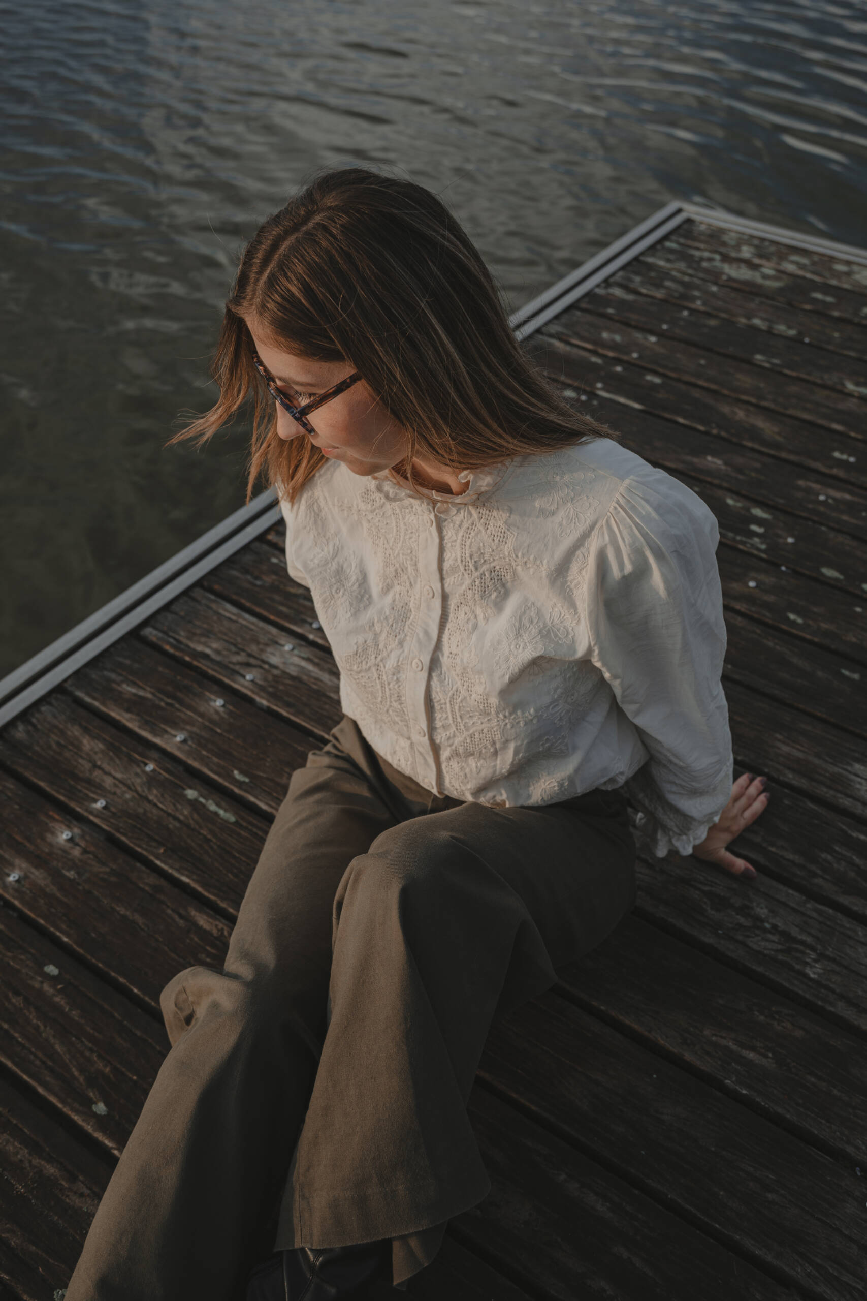 Portrait d’une femme assise sur un ponton en bois au-dessus d’un lac, photographiée en vue du dessus lors d’une séance portrait à La Roche-sur-Yon en Vendée, réalisée par Solène photographe.