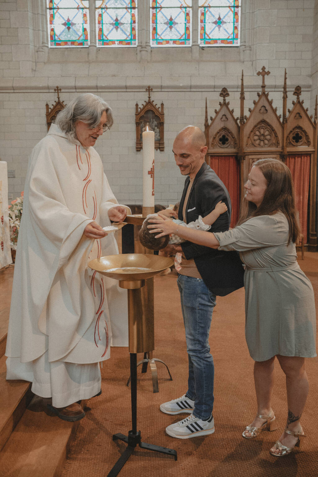 Maman qui fait le signe de croix sur le front de son enfant lors de son baptême à l'église de L'Herbergement en Vendée. Image réalisée par Solène photographe.