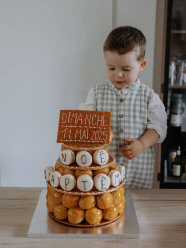 Enfant qui regarde la pièce montée de son baptême. Image réalisée par Solène photographe.