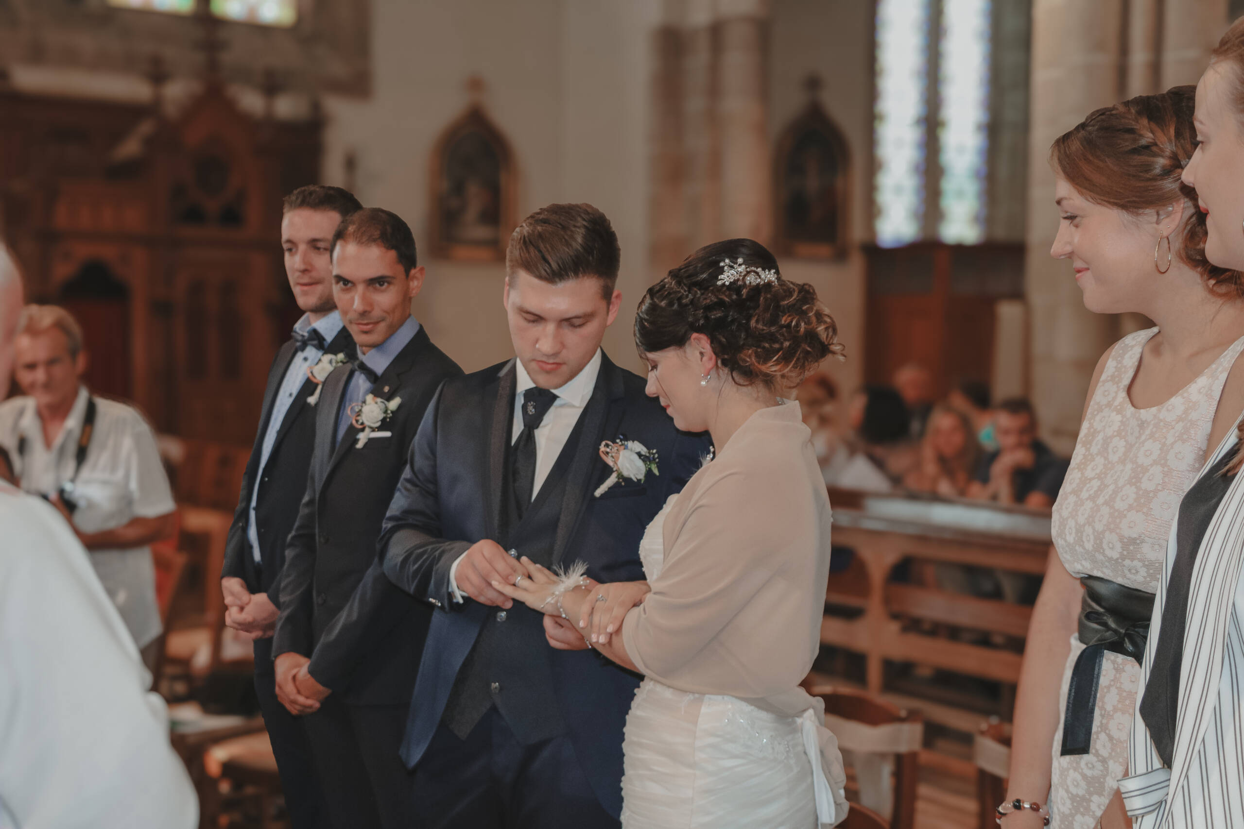 Mariés s'échangeant leurs alliances à l’église lors de leur cérémonie religieuse pendant leur mariage, réalisée par Solène photographe.