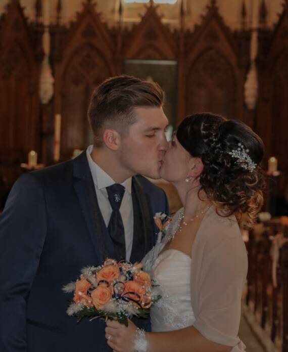 Mariés s'embrassant en sortant de l’église après leur cérémonie religieuse pendant leur mariage, réalisée par Solène photographe.