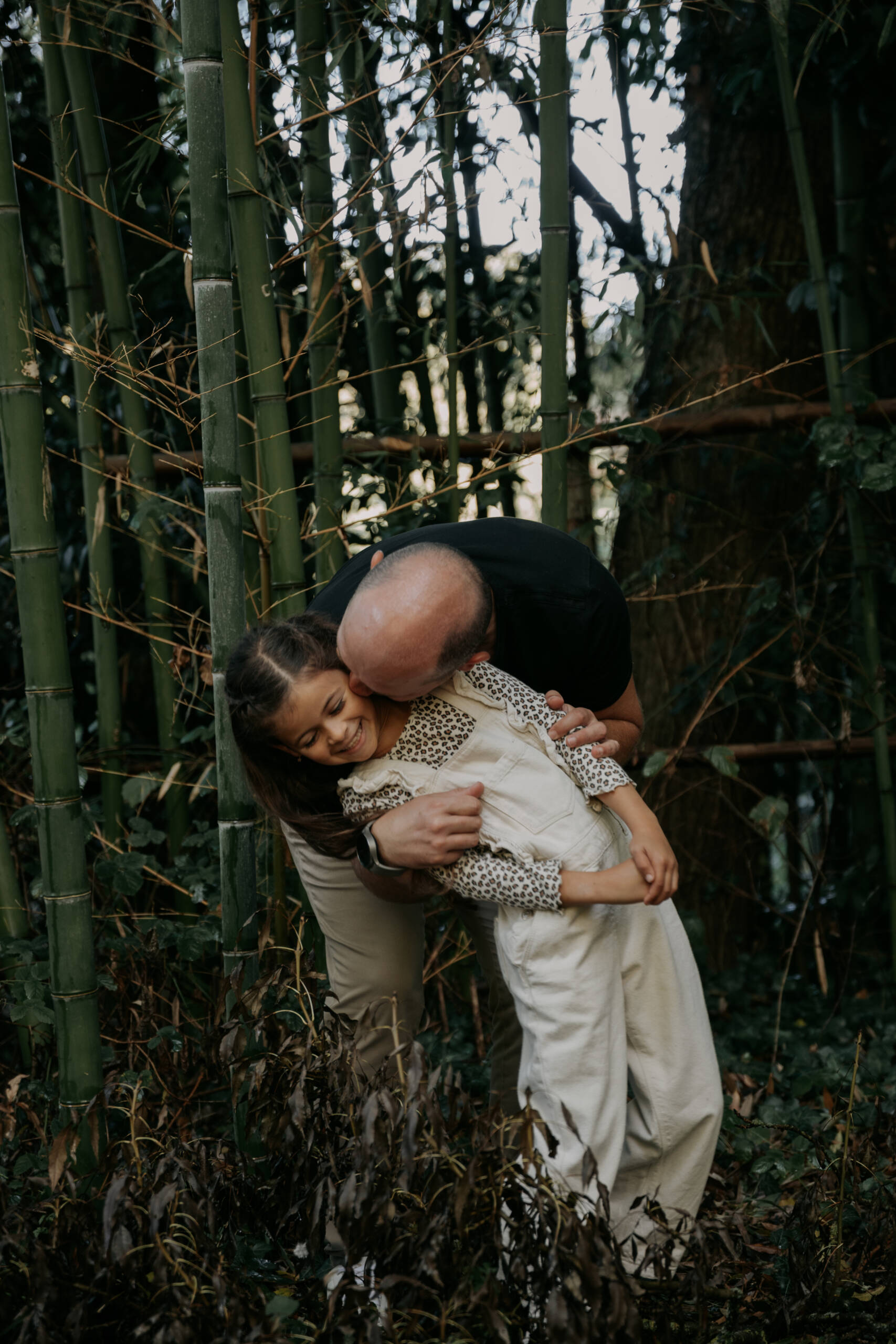 Parrain faisant un bisou sur la joue de sa filleule lors d’une séance photo famille à la Maison de la Rivière à Saint-Georges-de-Montaigu en Vendée, réalisée par Solène photographe.