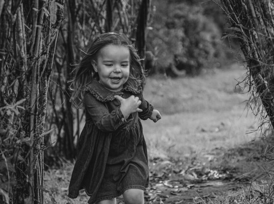 Enfant courant sous un tunnel végétal lors d’une séance photo famille à la Maison de la Rivière à Saint-Georges-de-Montaigu, réalisée par Solène photographe.