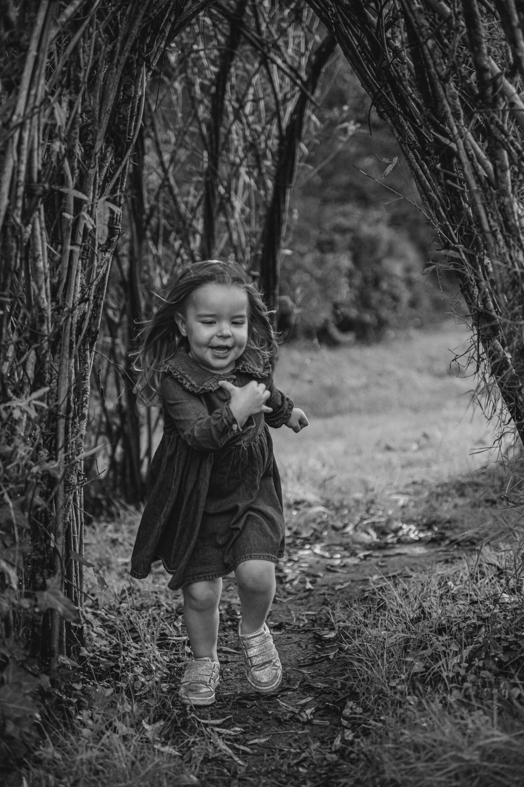 Enfant courant sous un tunnel végétal lors d’une séance photo famille à la Maison de la Rivière à Saint-Georges-de-Montaigu, réalisée par Solène photographe.