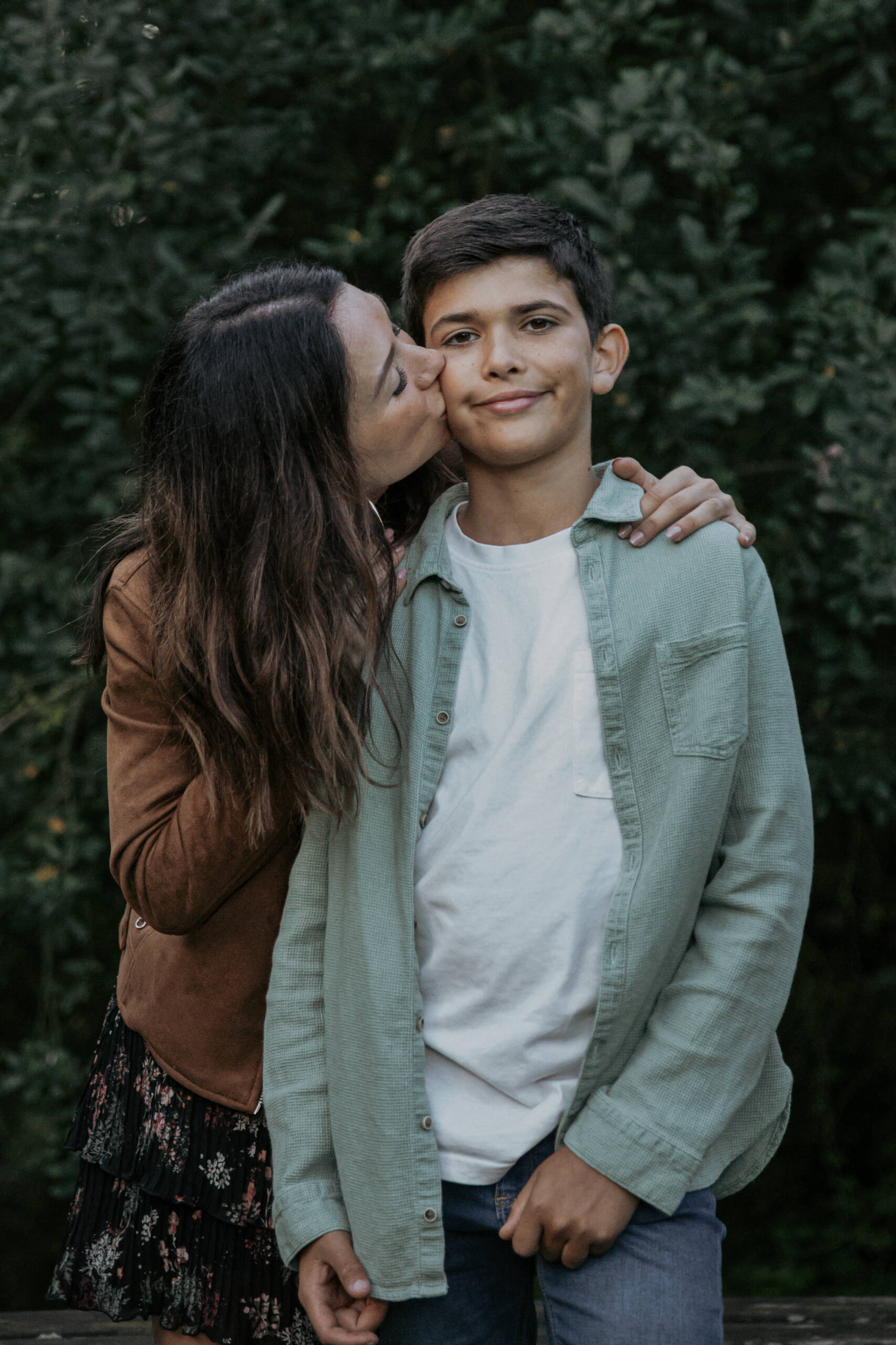 Marraine faisant un bisou sur la joue de son filleul lors d’une séance photo famille à la Maison de la Rivière à Saint-Georges-de-Montaigu en Vendée, réalisée par Solène photographe.