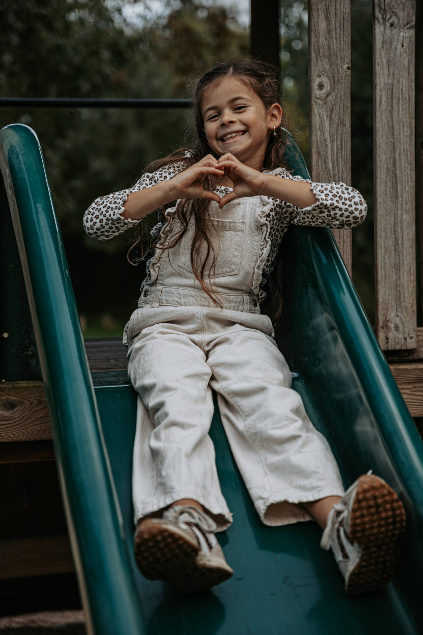 Enfant formant un cœur avec ses mains sur un toboggan lors d’une séance photo famille à la Maison de la Rivière à Saint-Georges-de-Montaigu, réalisée par Solène photographe.
