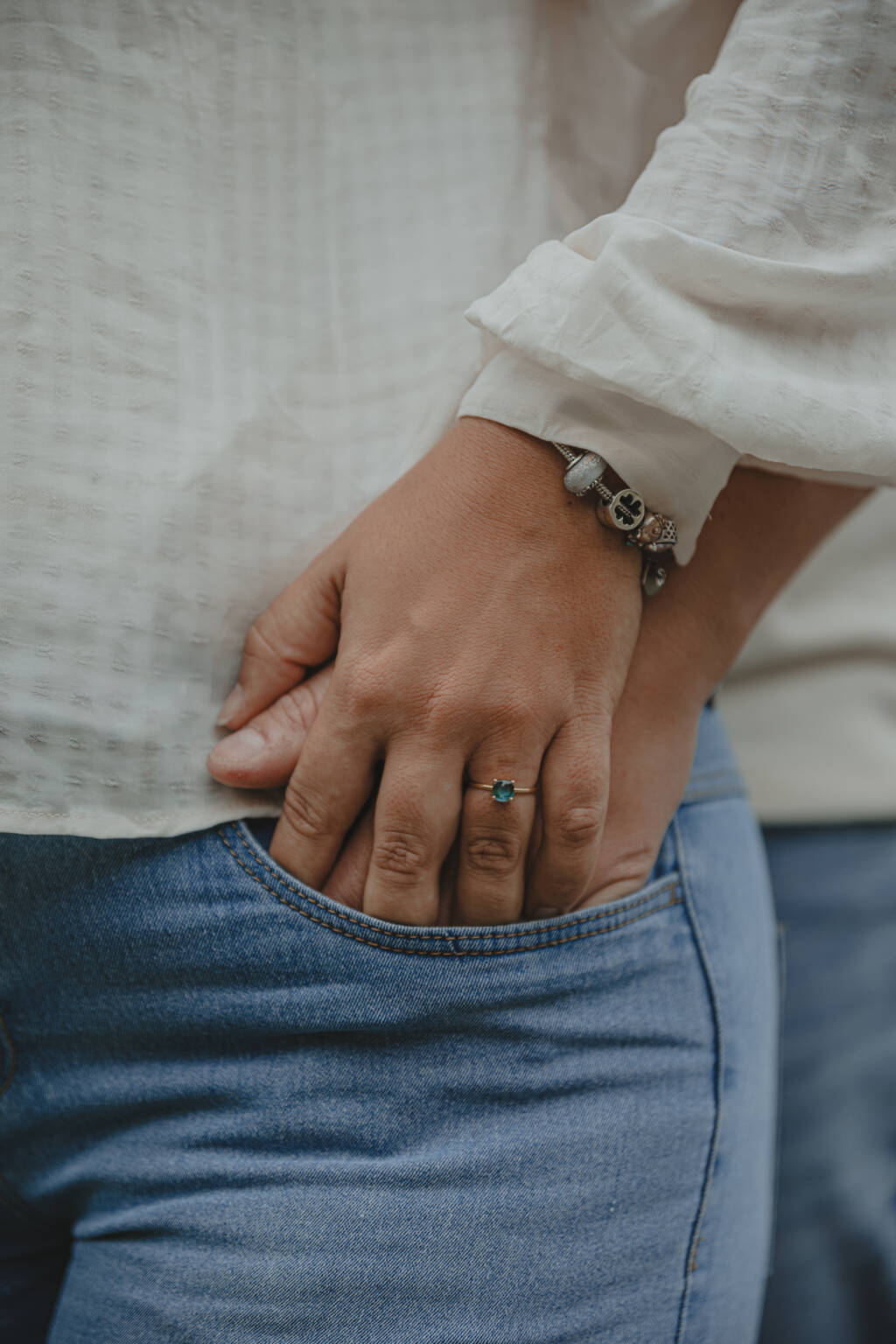 Main d’un homme et d’une femme réunies dans une poche de jean, mettant en valeur la bague de fiançailles à diamant bleu, lors d’une séance photo engagement à Clisson en Loire-Atlantique, réalisée par Solène photographe.
