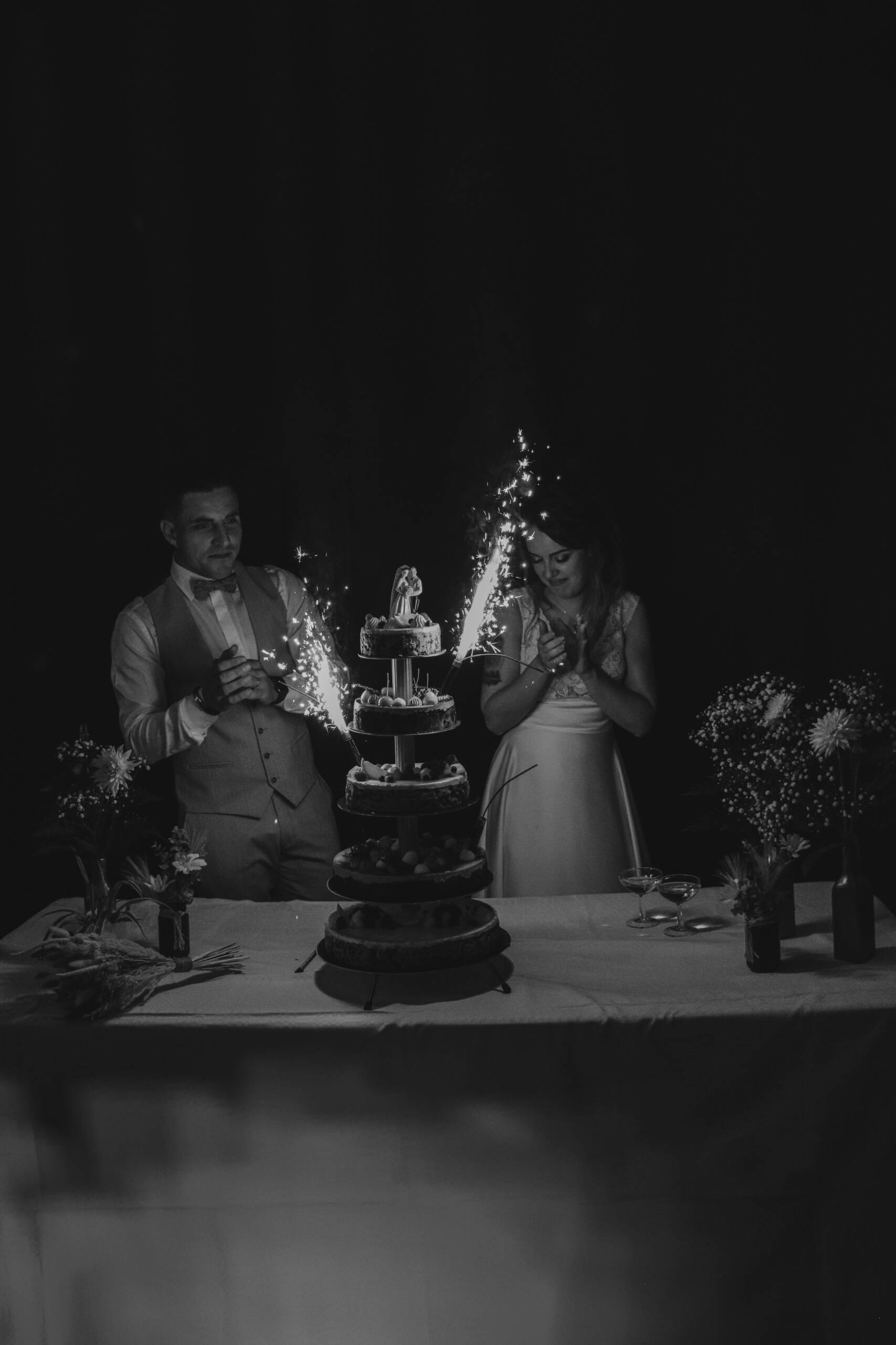 Mariés applaudissant en arrière plan de leur gâteau de mariage, réalisée par Solène photographe.
