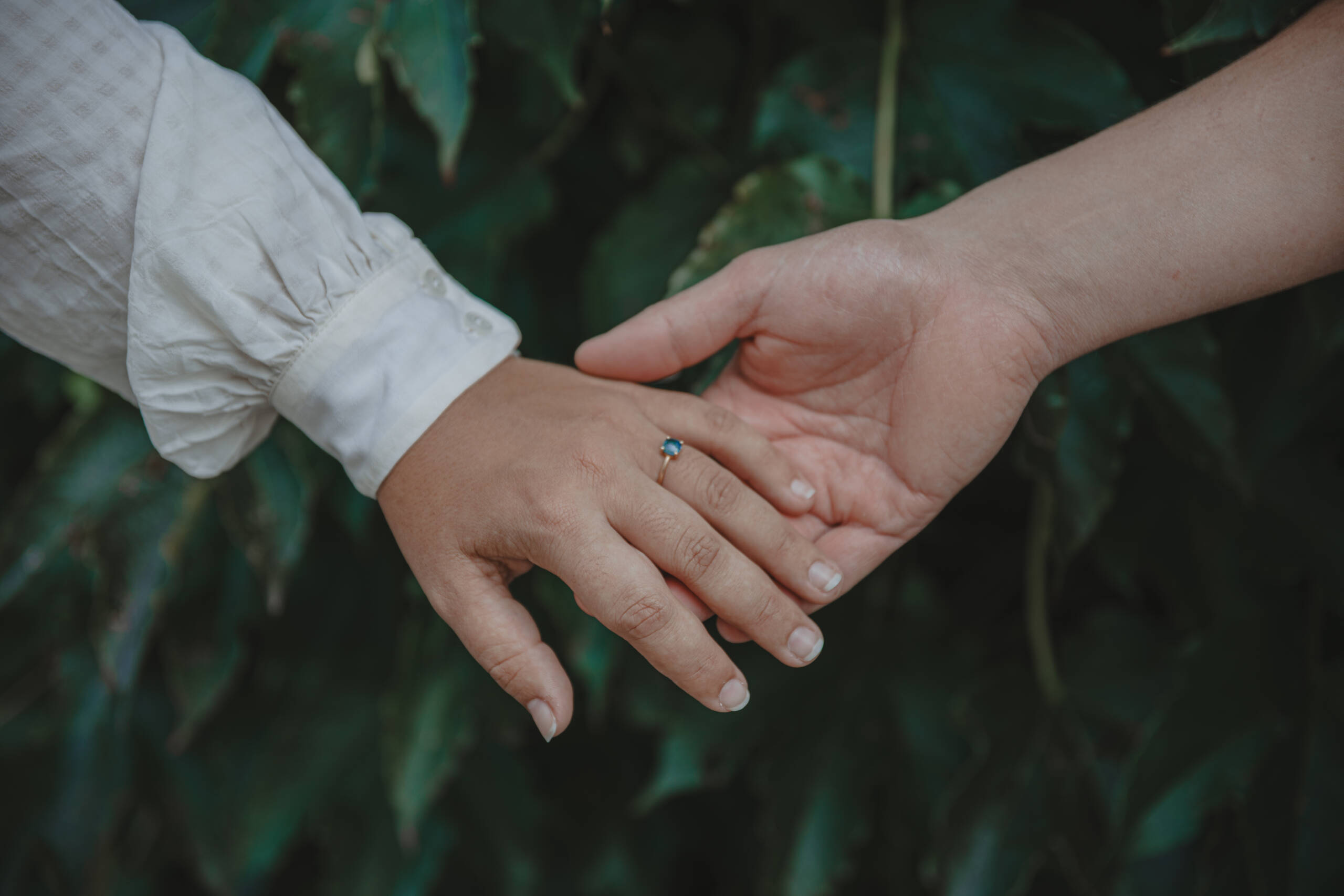 Mains réunies devant du lierre, mettant en valeur la bague de fiançailles à diamant bleu, lors d’une séance photo engagement à Clisson en Loire-Atlantique, réalisée par Solène photographe.