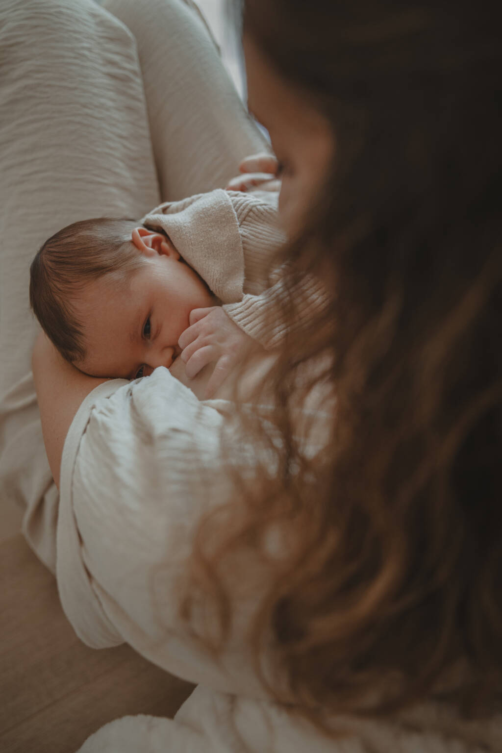 Maman donnant le sein à son bébé vue du dessus, lors d’une séance photo naissance à domicile à La Ferrière en Vendée, réalisée par Solène photographe.
