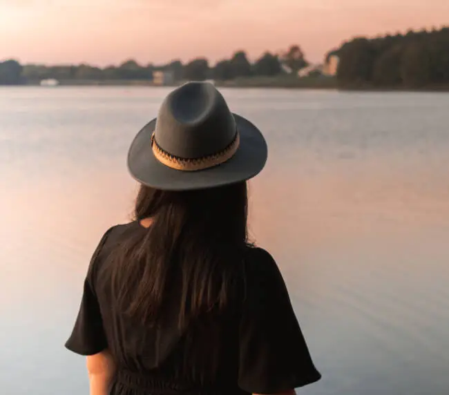 Portrait de Solène photographe se tenant debout face à un lac au lever du soleil, lors d’une séance portrait professionnel à La Roche-sur-Yon.