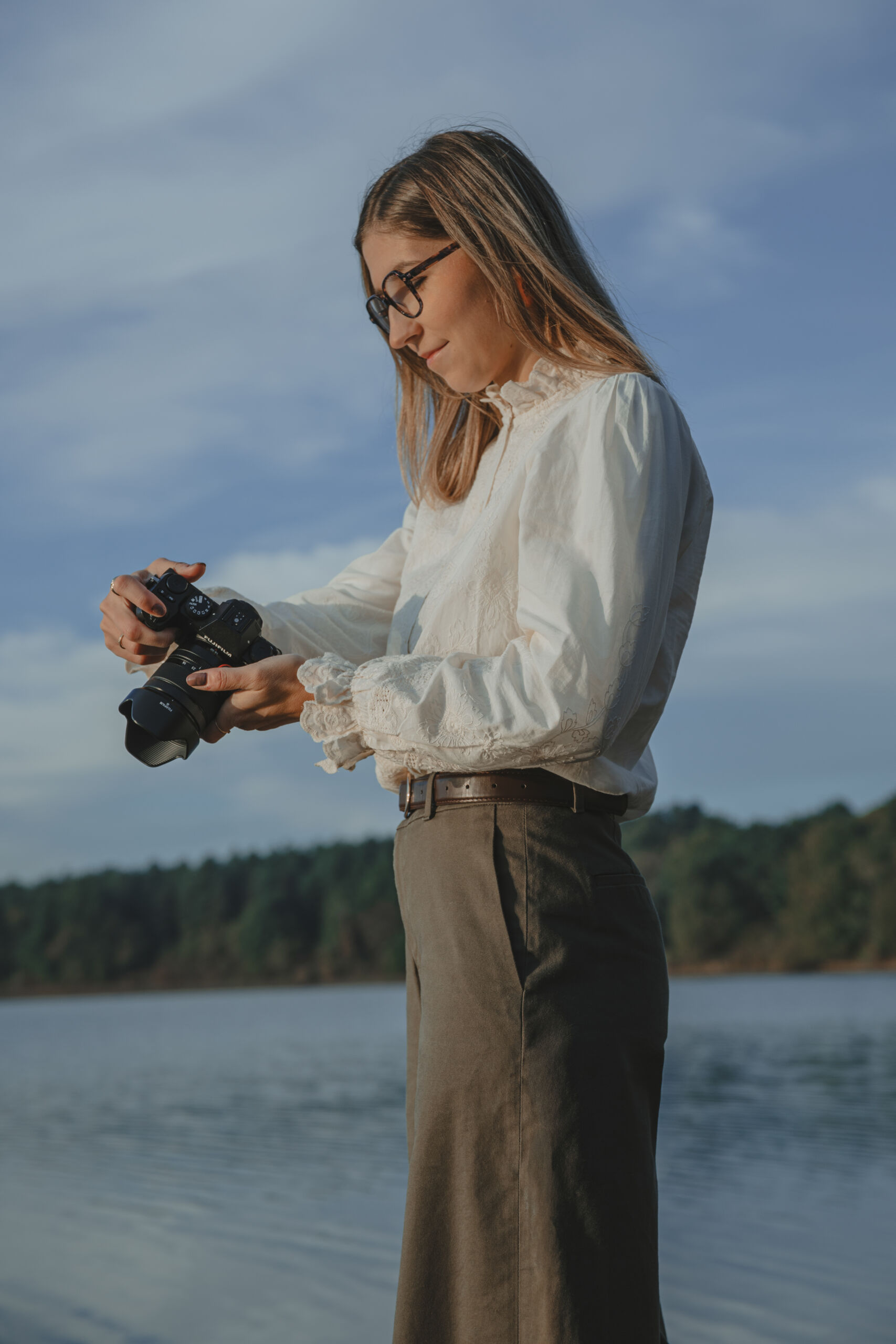 Femme regardant les photos sur l'écran de son appareil photo tenue dans ses mains, lors d’une séance portrait professionnel au lac de Moulin Papon à La Roche-sur-Yon en Vendée, réalisée par Solène photographe.