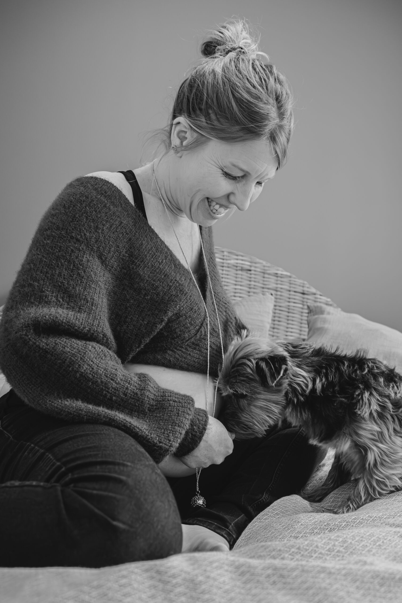 Femme enceinte sur un lit avec son chien, lors d’une séance photo grossesse à Dompierre-sur-Yon en Vendée, réalisée en noir et blanc par Solène photographe.