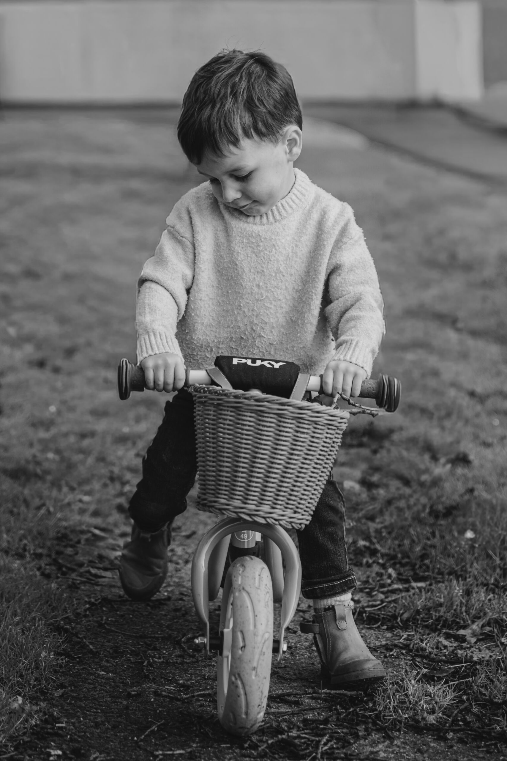 Enfant assis sur sa draisienne en extérieur, lors d’une séance photo grossesse à Dompierre-sur-Yon en Vendée, réalisée en noir et blanc par Solène photographe.