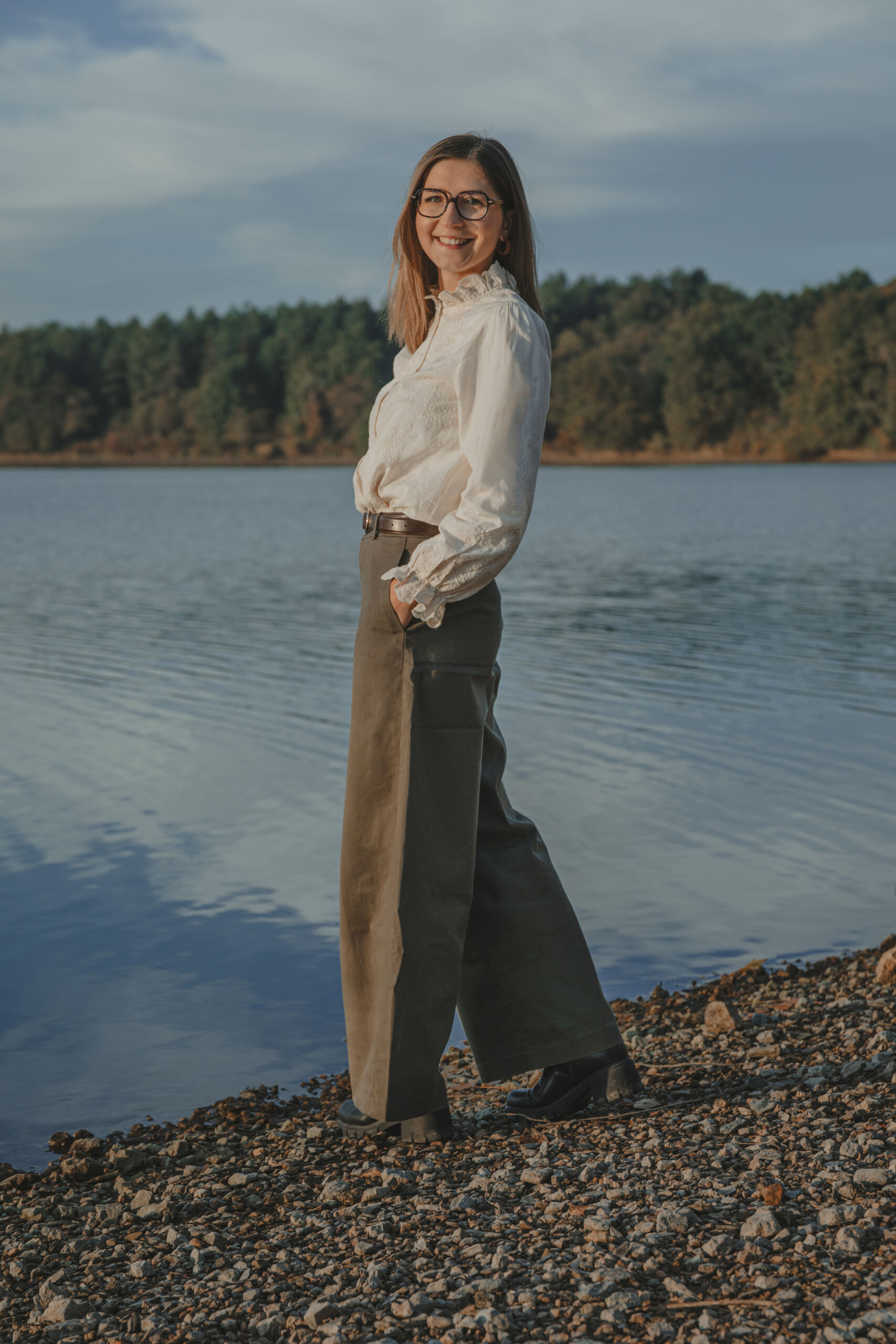 Portrait femme souriante debout près d'un lac, lors d’une séance portrait à La Roche-sur-Yon en Vendée, réalisée par Solène photographe.