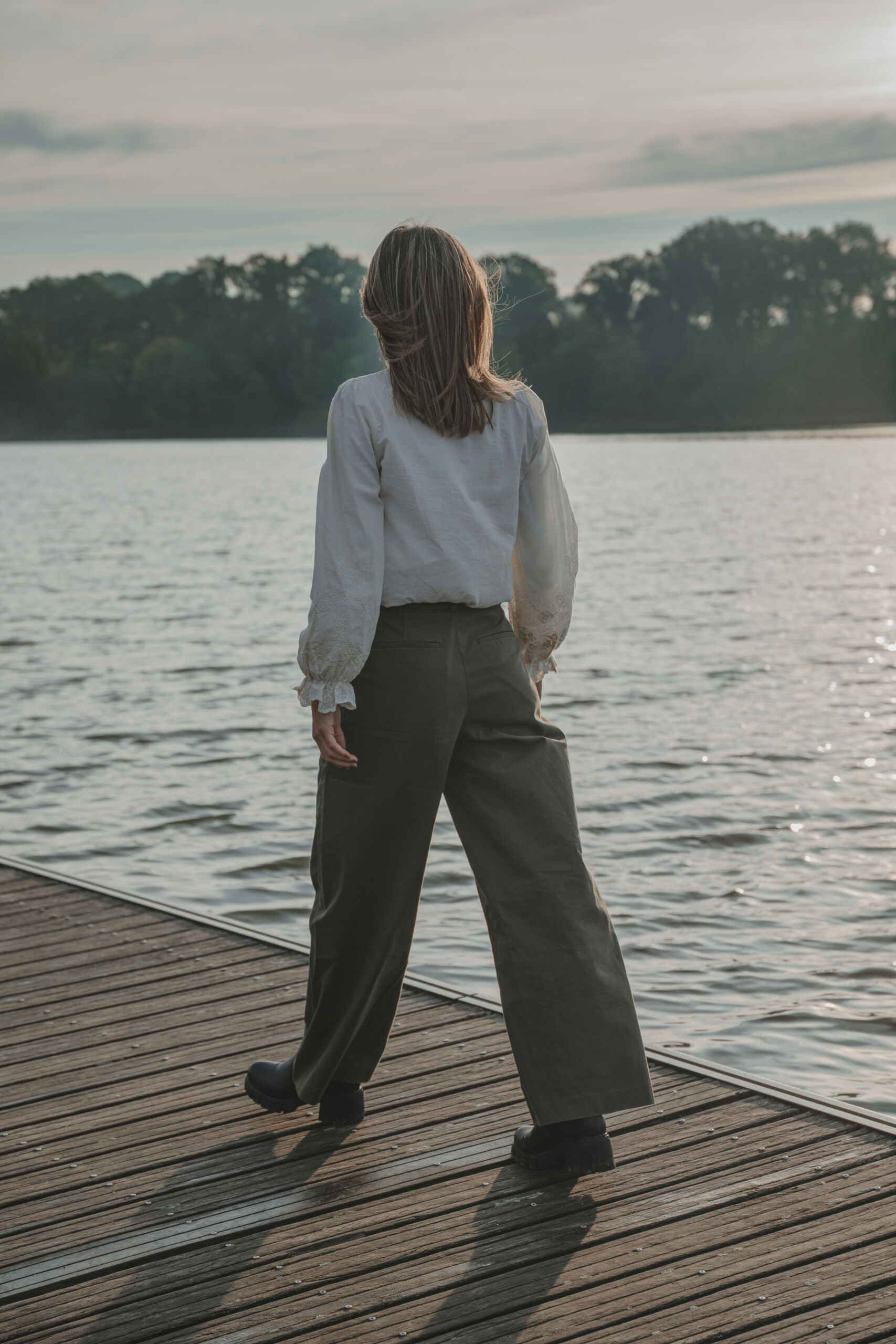 Portrait femme marchant sur un ponton en bois au-dessus d'un lac, lors d’une séance portrait à La Roche-sur-Yon en Vendée, réalisée par Solène photographe.