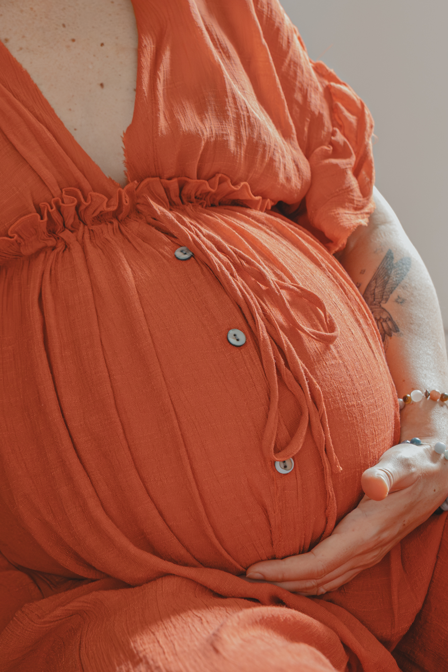 Gros plan d'un ventre arrondi avec une main placée en-dessous, lors d’un shooting confiance en soi à Montbert en Loire- Atlantique, réalisée par Solène photographe.