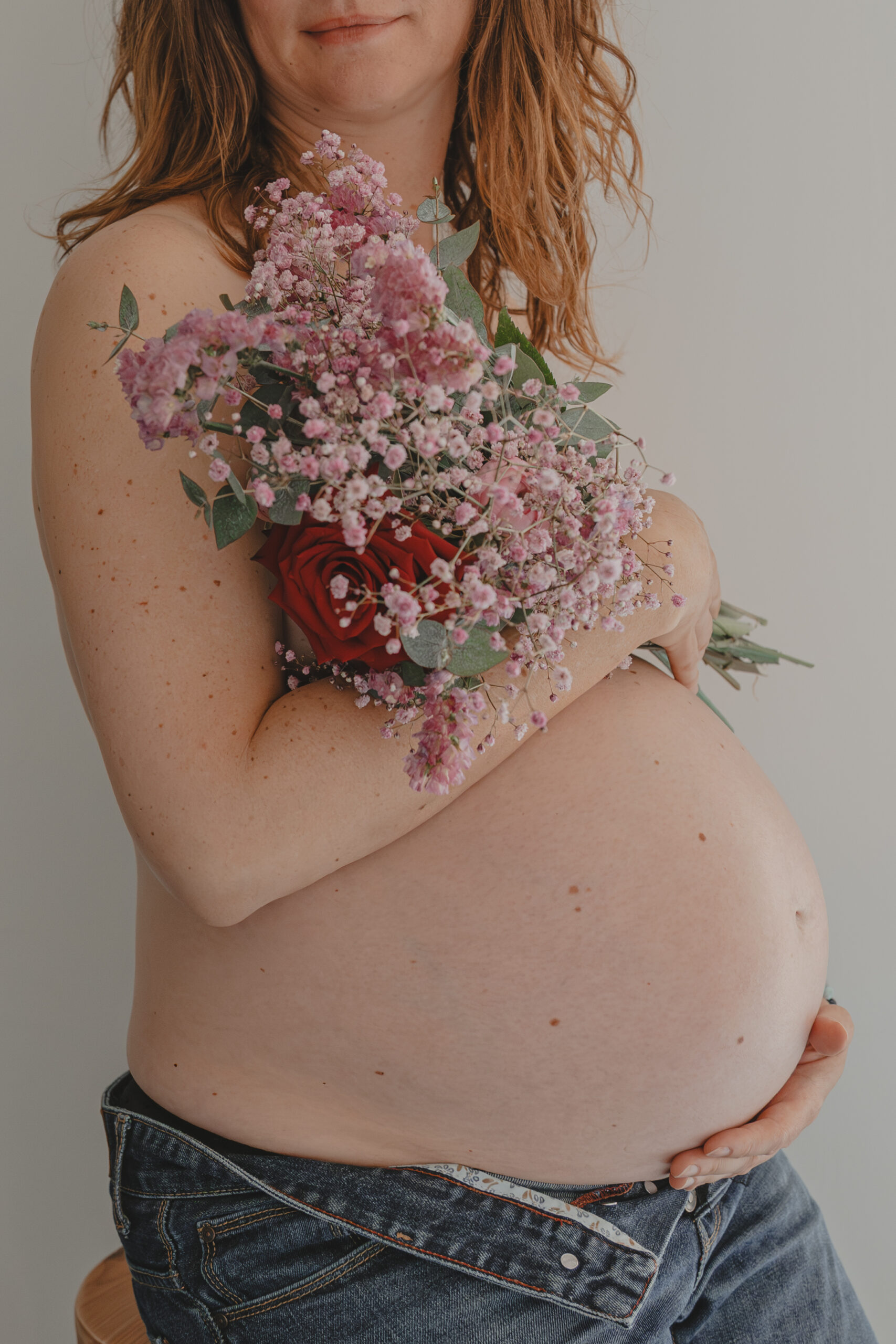 Femme enceinte cachant sa poitrine avec un bouquet de fleurs lors d’un shooting confiance en soi à Montbert en Loire- Atlantique, réalisée par Solène photographe.