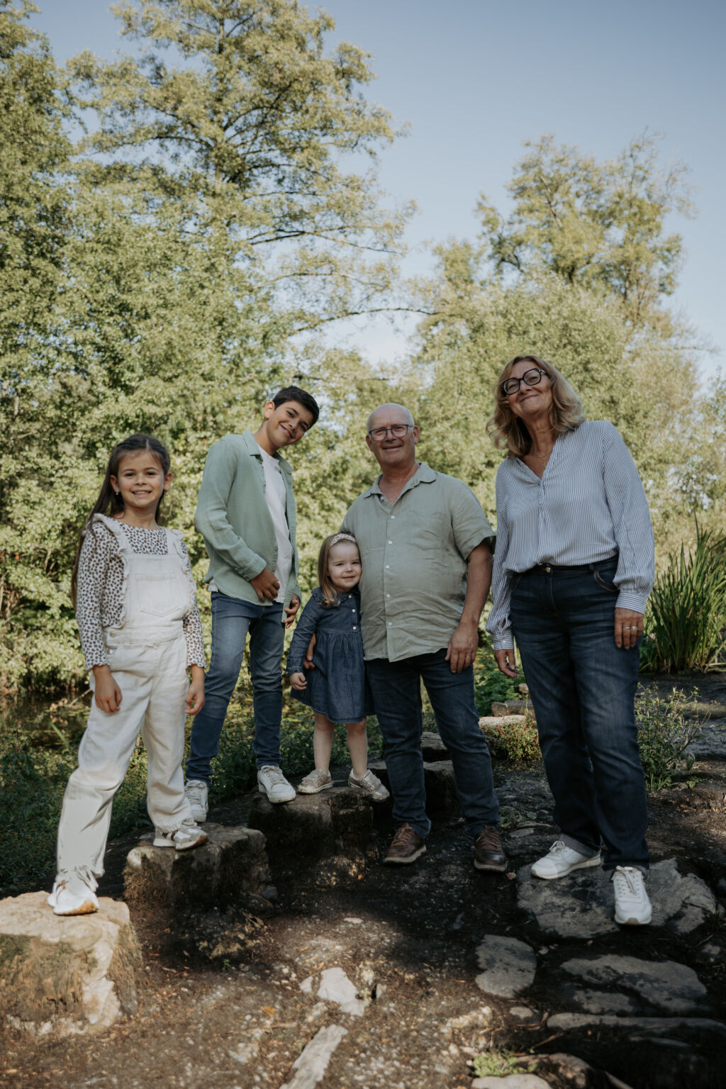 Grands-parents posant avec leurs petits-enfants sur une digue lors d’une séance photo famille à la Maison de la Rivière à Saint-Georges-de-Montaigu en Vendée, réalisée par Solène photographe.