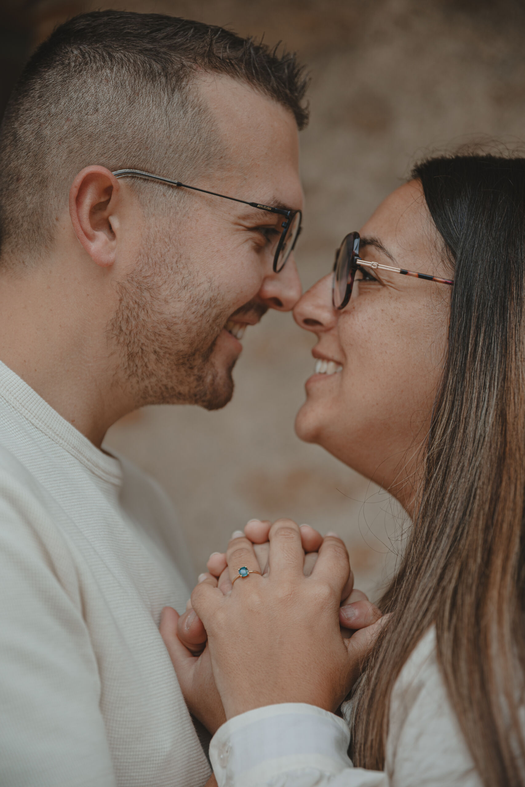 Couple faisant un bisou esquimau au-dessus de leurs mains liées, mettant en valeur la bague de fiançailles à diamant bleu, lors d’une séance photo engagement à Clisson en Loire-Atlantique, réalisée par Solène photographe.