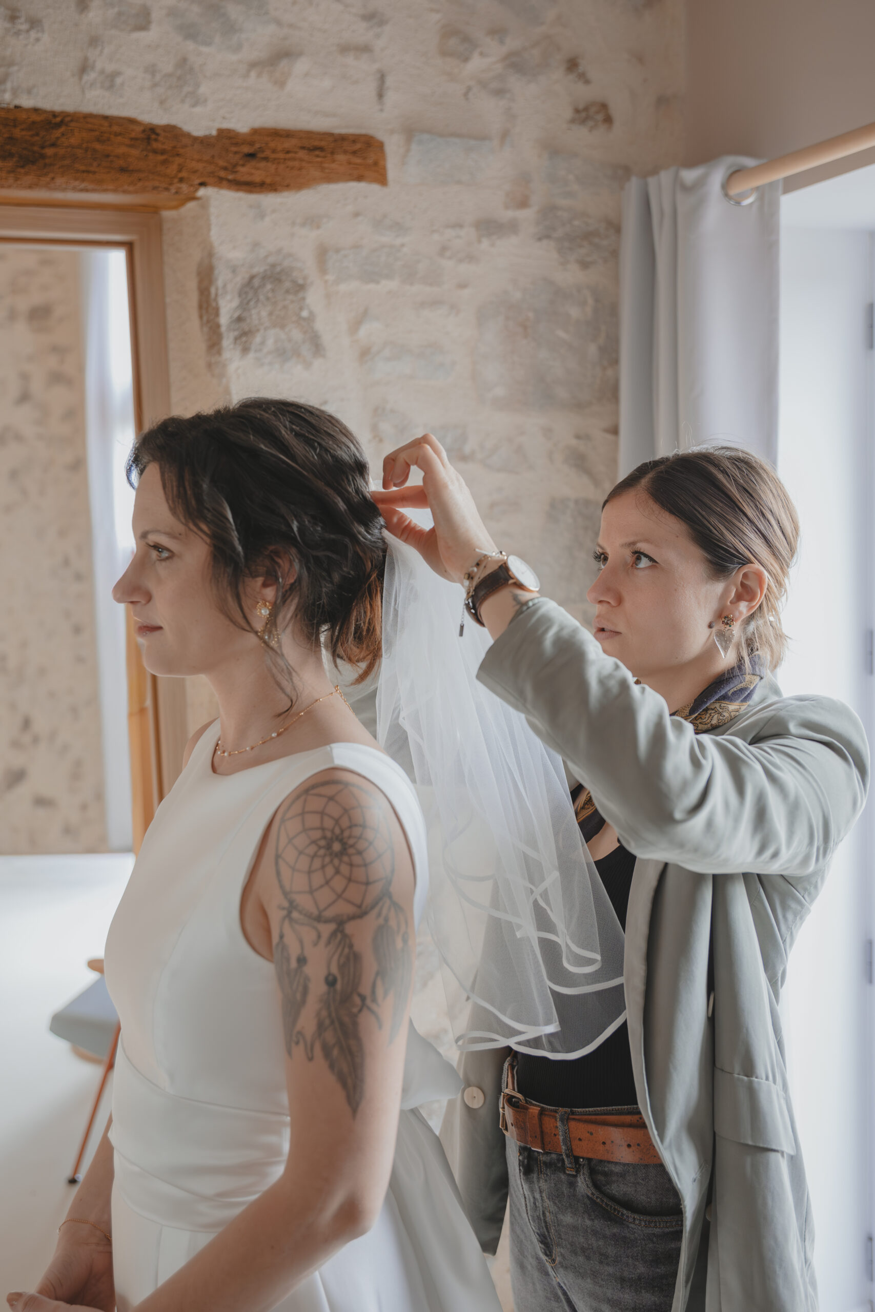 Coiffeuse mettant en place le voile de la mariée pendant les préparatifs de son mariage au Domaine Quatre Plumes aux Landes-Génusson en Vendée, réalisée par Solène photographe.