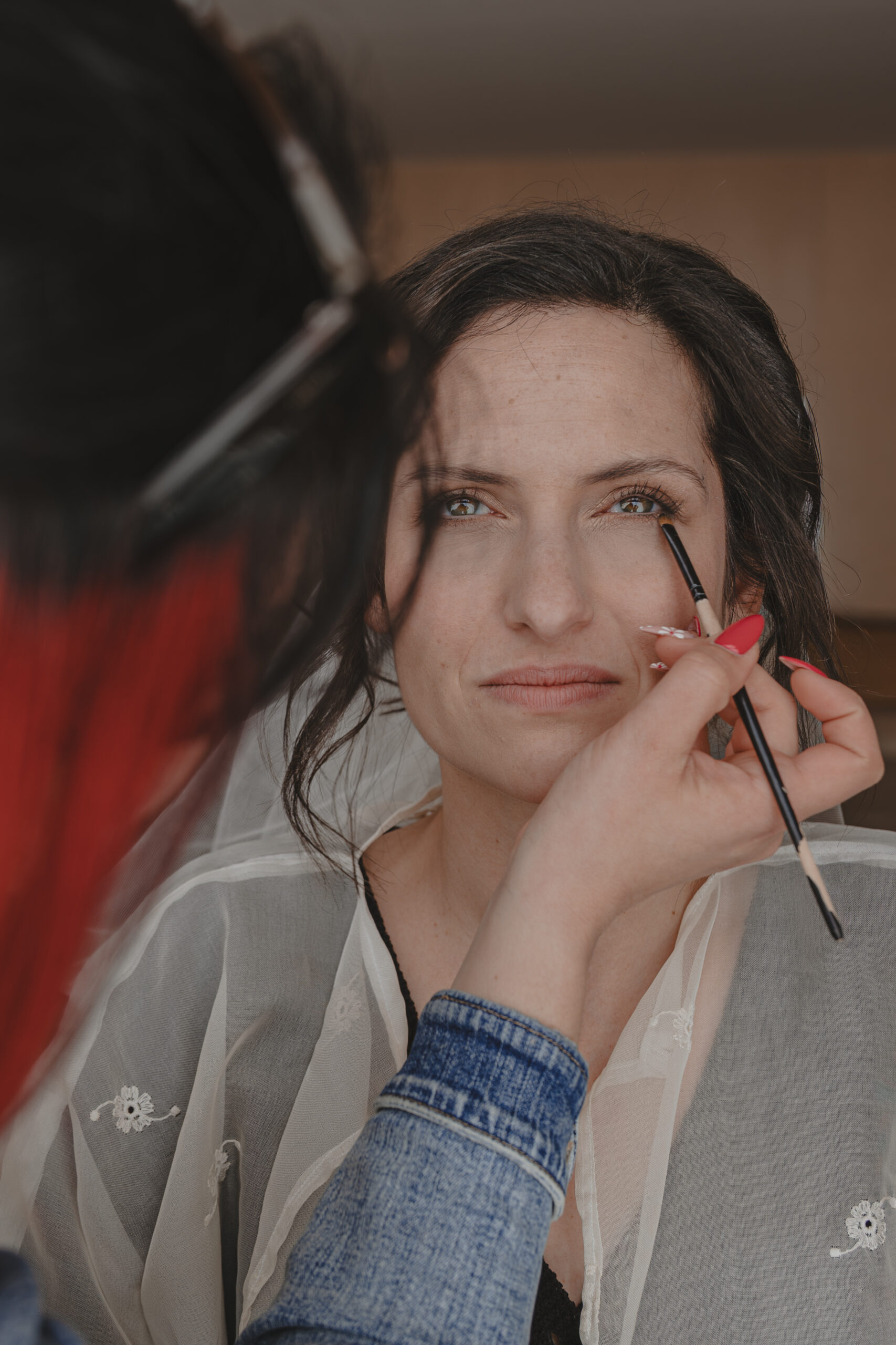 Mariée se faisant maquiller le dessous de l'oeil avec un pinceau fin pendant les préparatifs de son mariage au Domaine Quatre Plumes aux Landes-Génusson en Vendée, réalisée par Solène photographe.