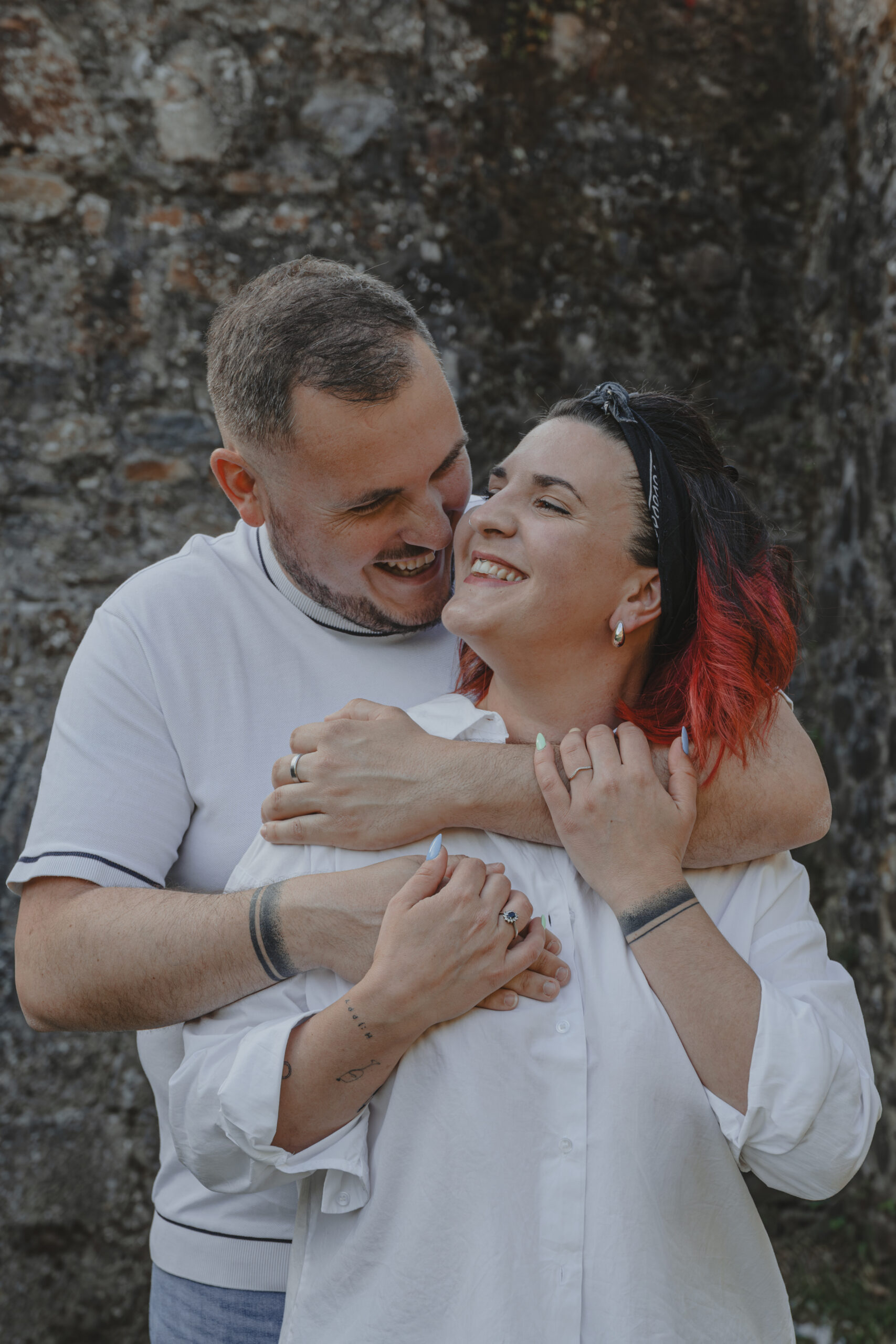 Homme souriant regardant en enlaçant par l'arrière sa future femme, lors d’une séance photo engagement au Parc des Remparts à Montaigu-Vendée, réalisée par Solène photographe.