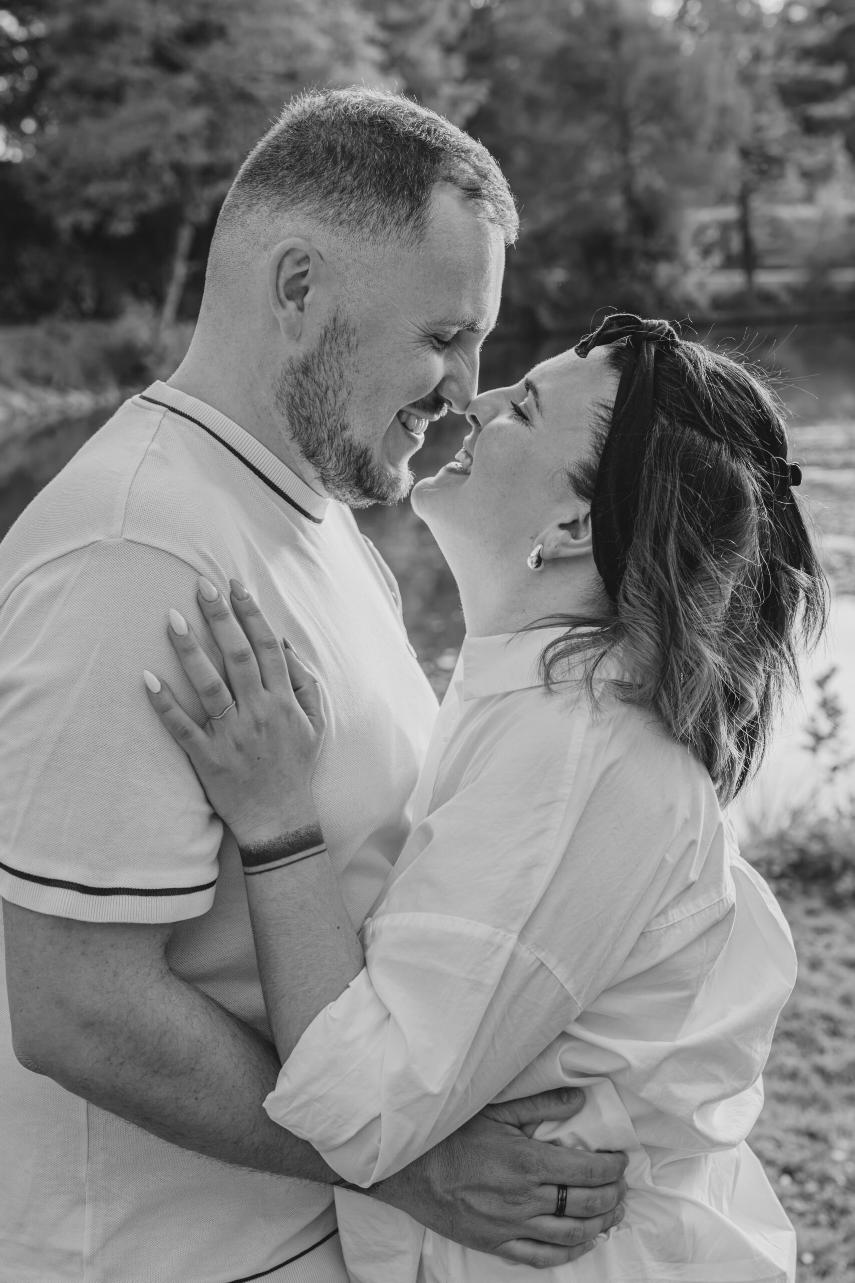 Couple se faisant un bisou esquimau en se regardant, lors d’une séance photo engagement au Parc des Remparts à Montaigu-Vendée, réalisée en noir et blanc par Solène photographe.