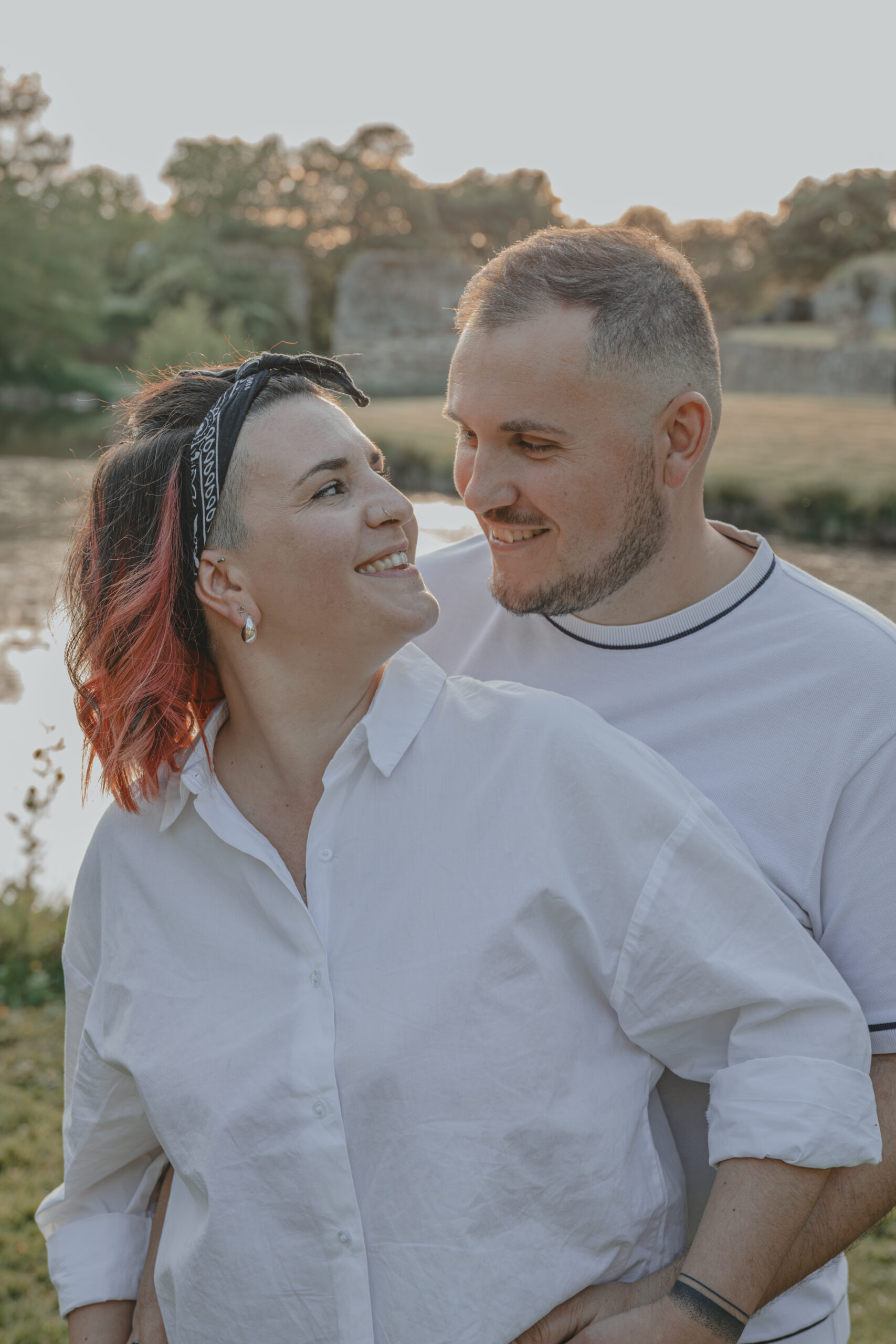 Couple se regardant en souriant au coucher du soleil, lors d’une séance photo engagement au Parc des Remparts à Montaigu-Vendée, réalisée par Solène photographe.