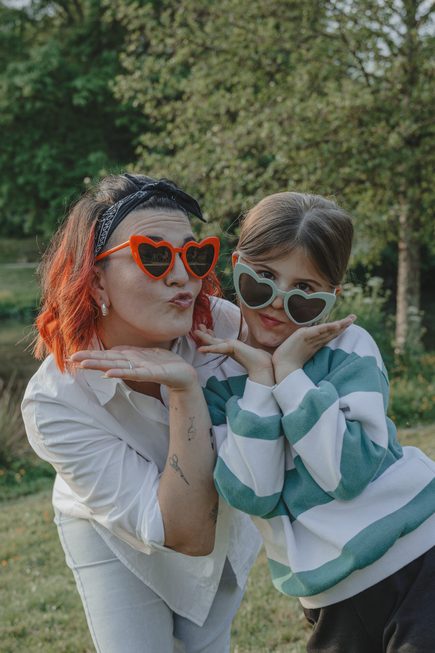 Mère et fille portant des lunettes cœur et faisant une bouche en cul de poule, lors d’une séance photo engagement au Parc des Remparts à Montaigu-Vendée, réalisée par Solène photographe.